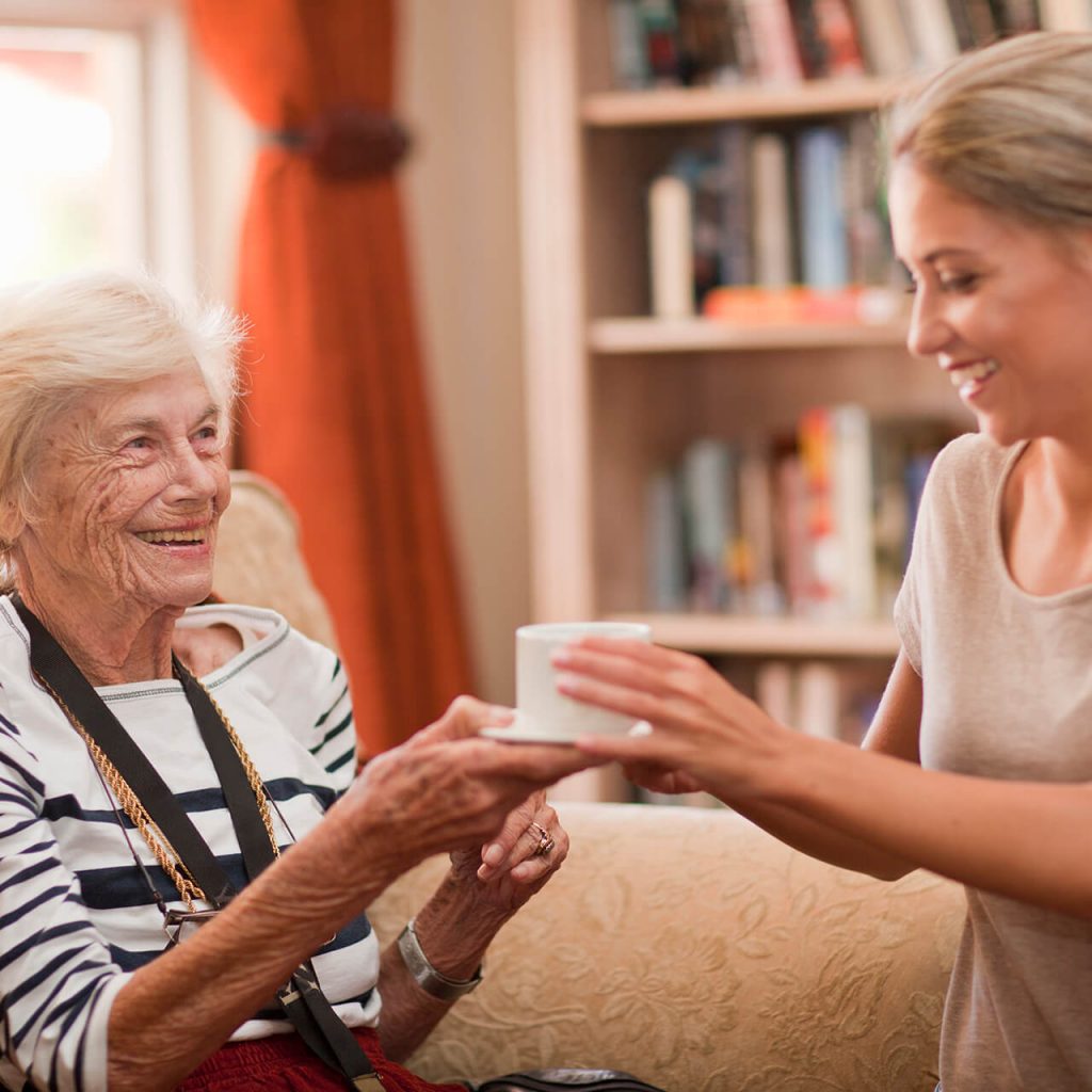 Seniorin erhält von einer Dame eine Tasse